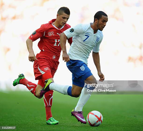 Theo Walcott of England is challenged by Granit Xhaka of Switzerland during the UEFA EURO 2012 group G qualifying match between England and...