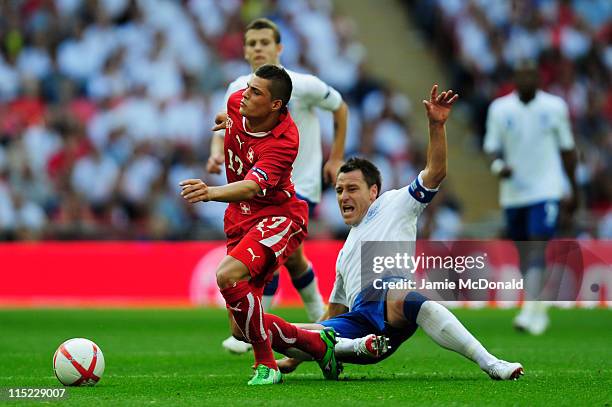 John Terry of England tackles Granit Xhaka of Switzerland during the UEFA EURO 2012 group G qualifying match between England and Switzerland at...