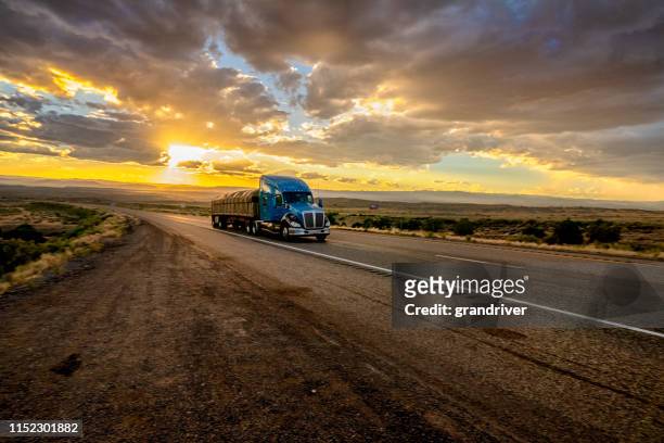 long haul semi truck speeding down a four lane highway in a beautiful sunset - articulated lorry stock pictures, royalty-free photos & images
