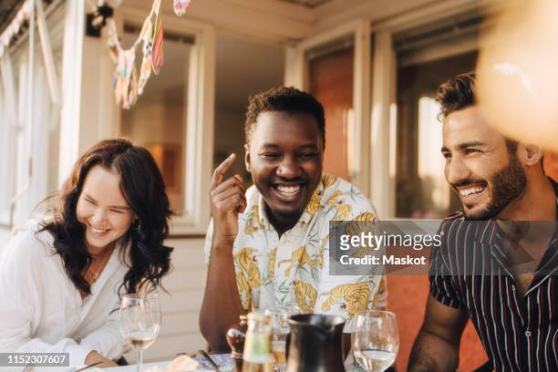 cheerful friends having fun at dining table during dinner party - 20 29 years stock pictures, royalty-free photos & images