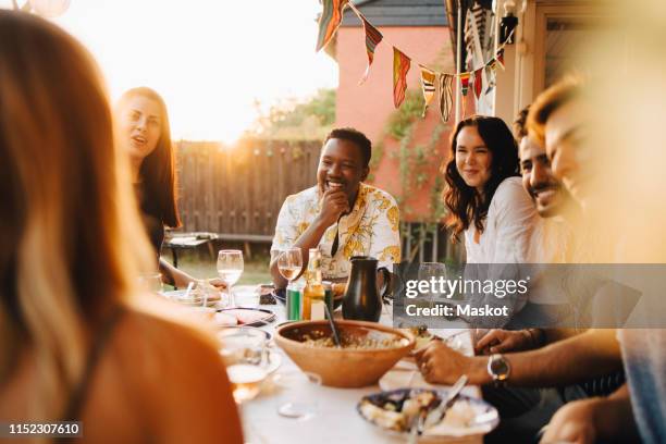 cheerful friends talking while enjoying dinner at dining table in party - inviter photos et images de collection