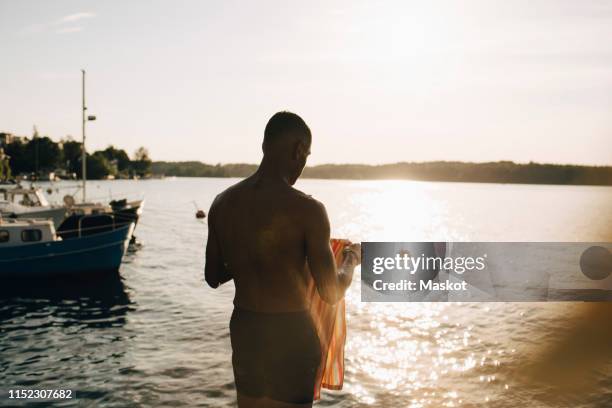 rear view of shirtless wet man with towel at lake in summer - boat in bath tub stock pictures, royalty-free photos & images