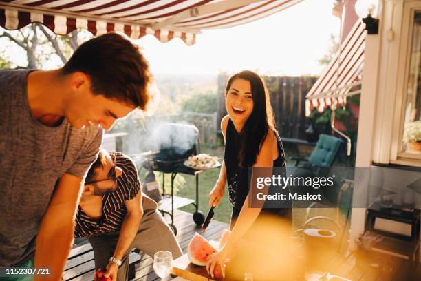 cheerful friends enjoying with fruits while preparing for dinner party - friends barbecue stock pictures, royalty-free photos & images
