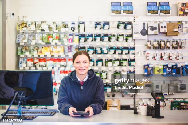 portrait of smiling mature saleswoman working in computer store - computer store photos et images de collection