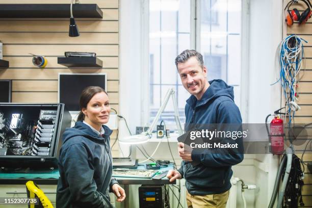 portrait of confident smiling computer engineers working in electronics store - computer store photos et images de collection