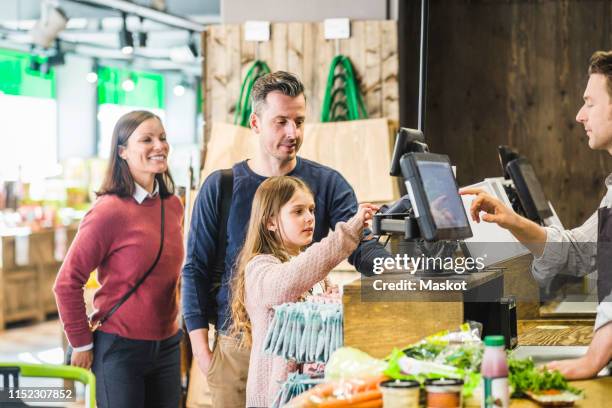 cute girl typing pin code at checkout counter in supermarket by family - paying supermarket foto e immagini stock