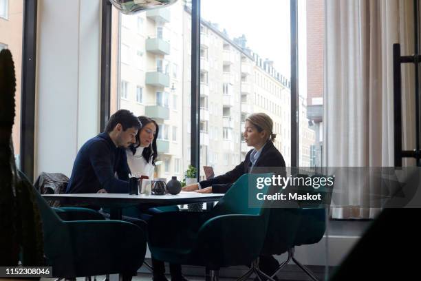 real estate agent discussing with couple in office - real estate office stockfoto's en -beelden