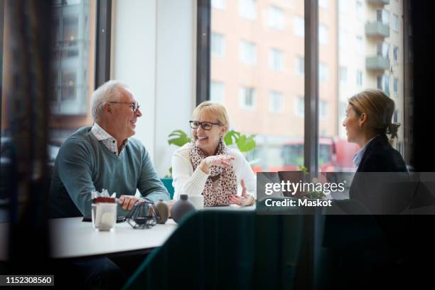 smiling senior couple talking while sitting with real estate agent in office - financial planning couple stock pictures, royalty-free photos & images