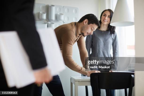 woman looking at real estate agent while man signing documents at new home - house rental bildbanksfoton och bilder