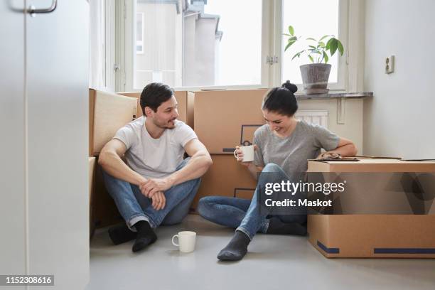 smiling couple talking while enjoying coffee during moving house - coffee package stock-fotos und bilder