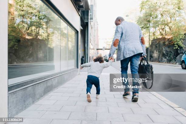 rear view of father and daughter walking on sidewalk in city - stockholm building stock pictures, royalty-free photos & images