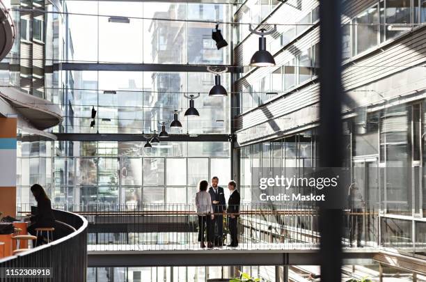 business colleagues discussing at atrium in office - atrio fotografías e imágenes de stock