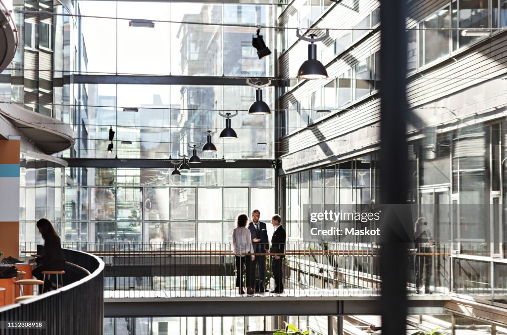 Business colleagues discussing at atrium in office