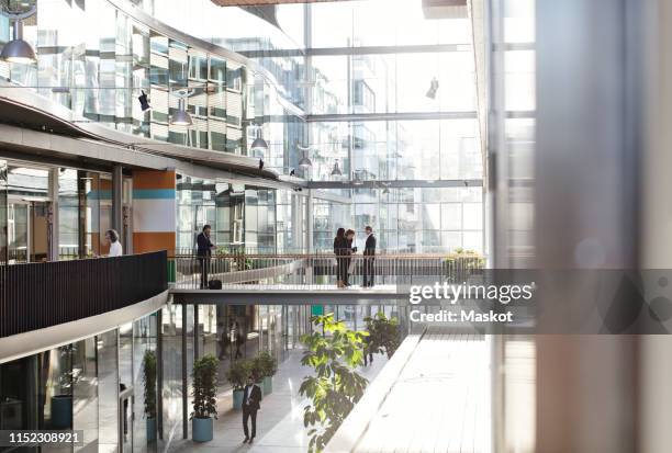 male and female business people standing at modern office atrium - atrium architektonisches detail stock-fotos und bilder