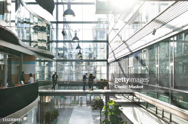 business people standing in atrium at modern office - atrium stock pictures, royalty-free photos & images