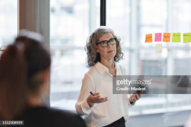 senior confident businesswoman giving presentation in board room at office - ladies marketing day stock-fotos und bilder