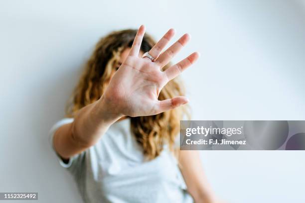 portrait of woman covering her face with her hand - hand stop stock-fotos und bilder