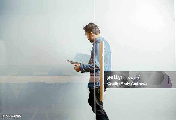 businessman walking in corridor reading notes - glass entrance stock pictures, royalty-free photos & images