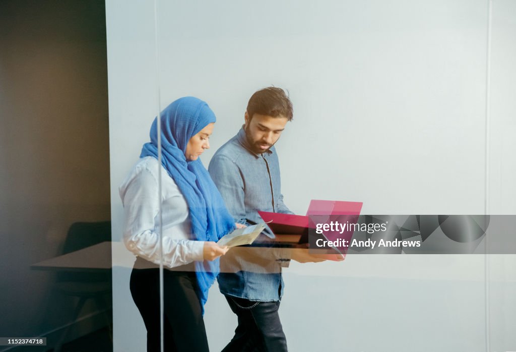 Colleagues walking in corridor discussing a project