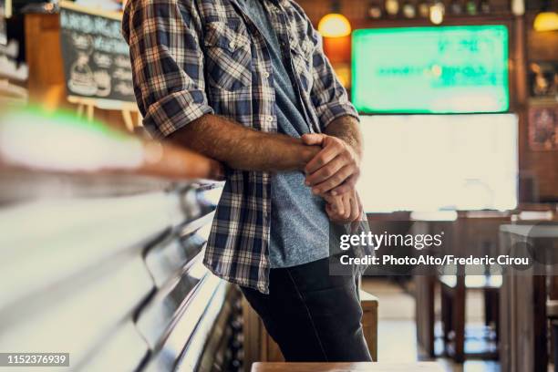 man leaning against bar counter - bar man t shirt stock-fotos und bilder