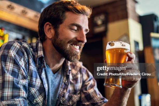 man looking at beer glass - man sipping beer smiling stockfoto's en -beelden