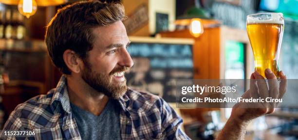 man looking at beer glass - bar man t shirt stock-fotos und bilder