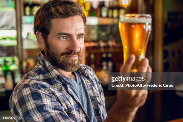 man looking at beer glass - bar man t shirt stock-fotos und bilder