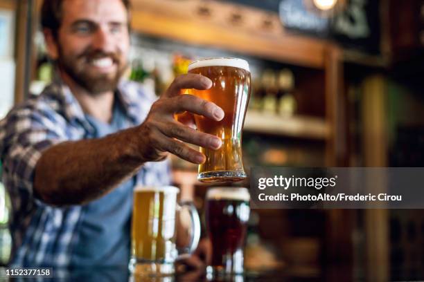 smiling man serving beer - bar man t shirt stock-fotos und bilder