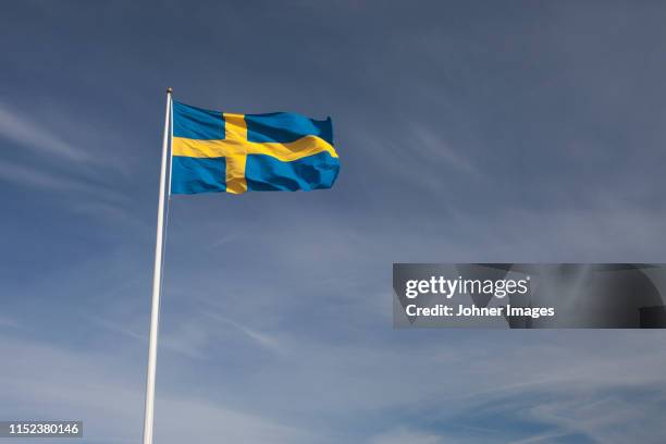 swedish flag against sky - sweden flag stock-fotos und bilder