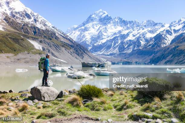 ein junger mann genießt die herrliche aussicht auf den gletscher in mt cook, neuseeland - mt cook stock-fotos und bilder