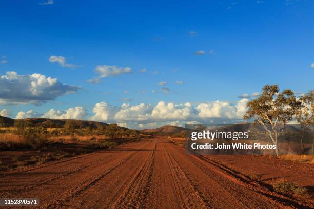 red dirt outback road near mount tom price. - country road australia stockfoto's en -beelden