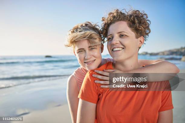 young lesbian couple on beach - urlaub frau strand sonne blond kurze haare stock-fotos und bilder