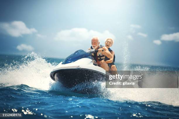 senior couple jet skiing. - seniors extreme sports stock pictures, royalty-free photos & images