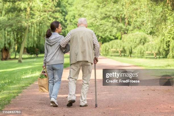 betreuer – frau hilft älteren mann beim einkaufen - spazierstock stock-fotos und bilder