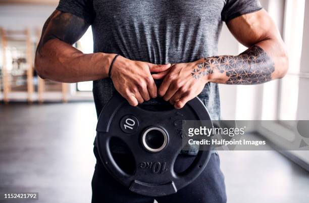 midsection of young mixed race man doing exercise in gym. - mann gewichtheben stock-fotos und bilder