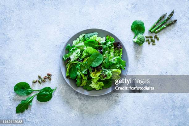 gezond eten: verse groene salade geschoten van bovenaf op grijze achtergrond - groene salade stockfoto's en -beelden