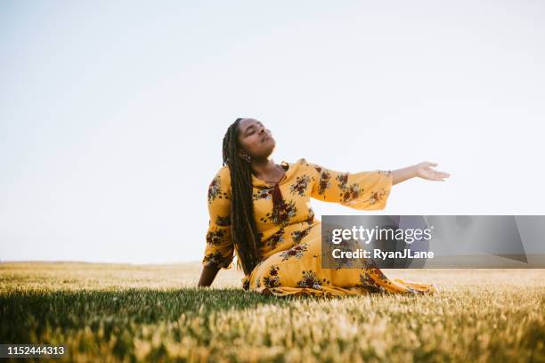 praying african young woman in field - women suffrage stock pictures, royalty-free photos & images