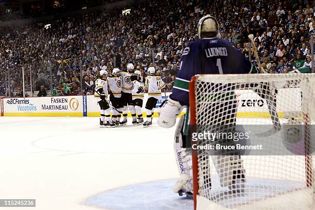 Roberto Luongo of the Vancouver Canucks looks down as Mark Recchi of the Boston Bruins celebrates with his teammates after scoring a goal in the...