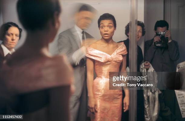 Eartha Kitt standing in front of a mirror looking at her self as she is getting dressed by Givenchy. She is in shock seeing her reflection in her...