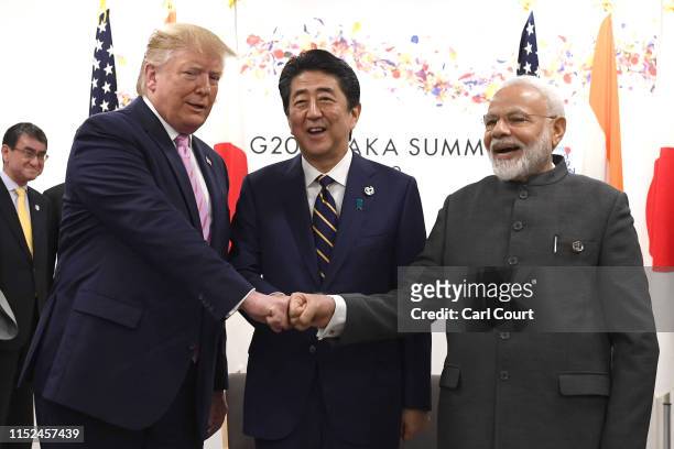 President Donald Trump does a fist bump with Japan's Prime Minister, Shinzo Abe, and India's Prime Minister, Narendra Modi, during a trilateral...