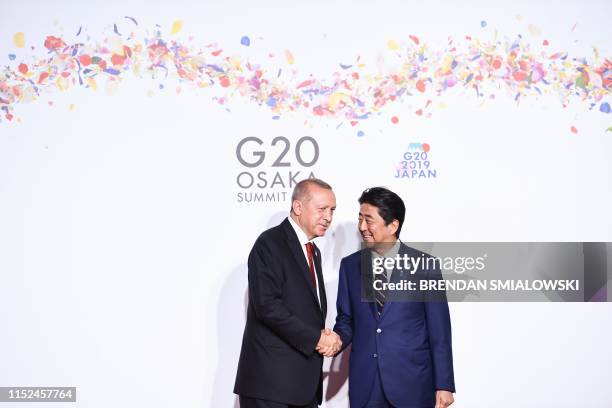 Turkey's President Recep Tayyip Erdogan is welcomed by Japanese Prime Minister Shinzo Abe upon his arrival for a welcome and family photo session at...