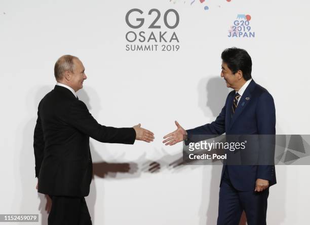 Russian President Vladimir Putin welcomed by Japanese Prime Minister Shinzo Abe for a family photo session on the first day of the G20 summit on June...