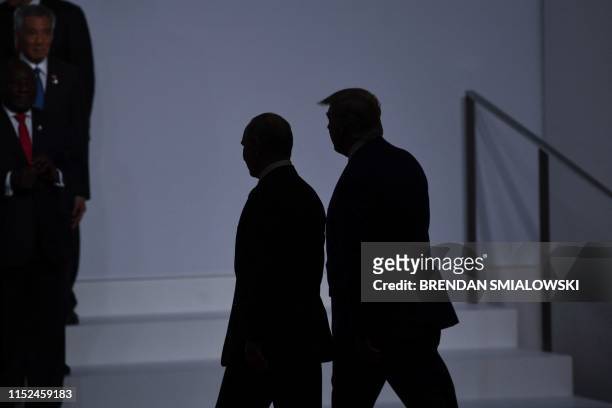 President Donald Trump walks with Russia's President Vladimir Putin before taking a family photo at the G20 Summit in Osaka on June 28, 2019.