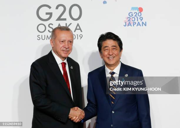 Turkey's President Recep Tayyip Erdogan is welcomed by Japanese Prime Minister Shinzo Abe upon his arrival for a family photo session at the G20...