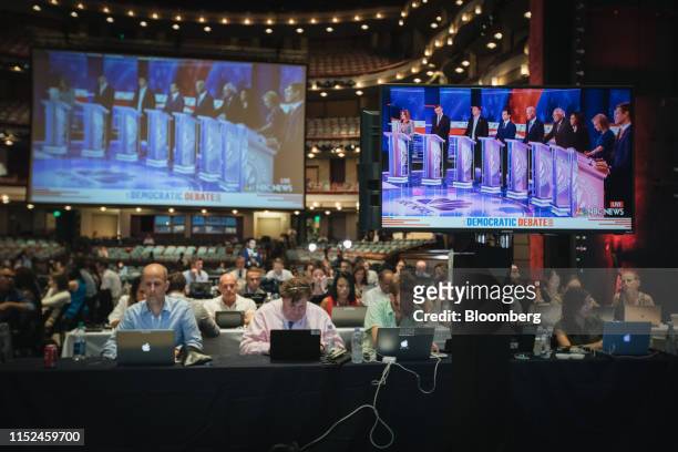 Democratic presidential candidates are shown on a screen as members of the media work during the Democratic presidential candidate debate in Miami,...
