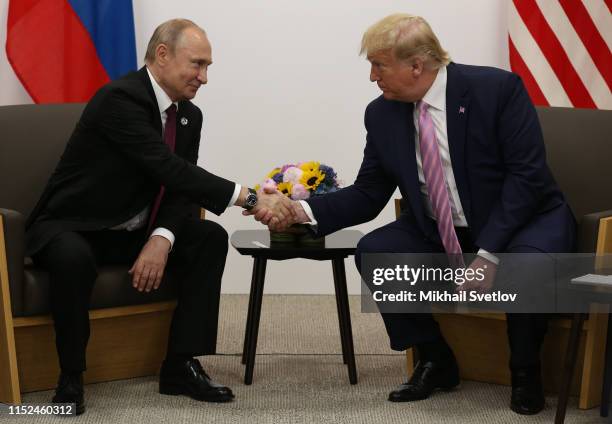 President Donald Trump greets Russian President Vladimir Putin during their bilateral meeting at the G20 Osaka Summit 2019, in Osaka, Japan, June...