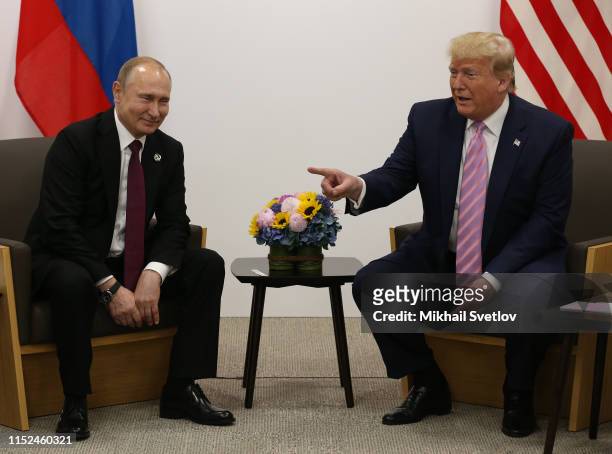 President Donald Trump points to Russian President Vladimir Putin during their bilateral meeting at the G20 Osaka Summit 2019, in Osaka, Japan, June...