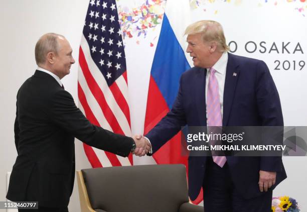 Russian President Vladimir Putin and US President Donald Trump shake hands during a meeting on the sidelines of the G20 summit in Osaka on June 28,...