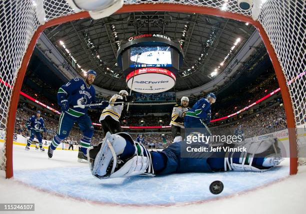 Roberto Luongo of the Vancouver Canucks has the puck go by him in the second period, while teammates Christian Ehrhoff and Andrew Alberts look on...