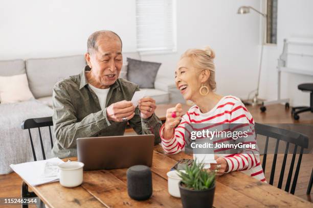 自宅で、笑顔でオンラインバンキングを行うシニアカップル - 夫婦 ストックフォトと画像